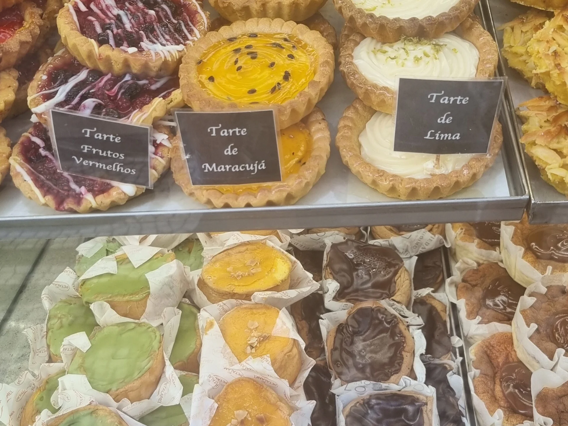 Assorted fruit tarts and pastries displayed in a bakery case.