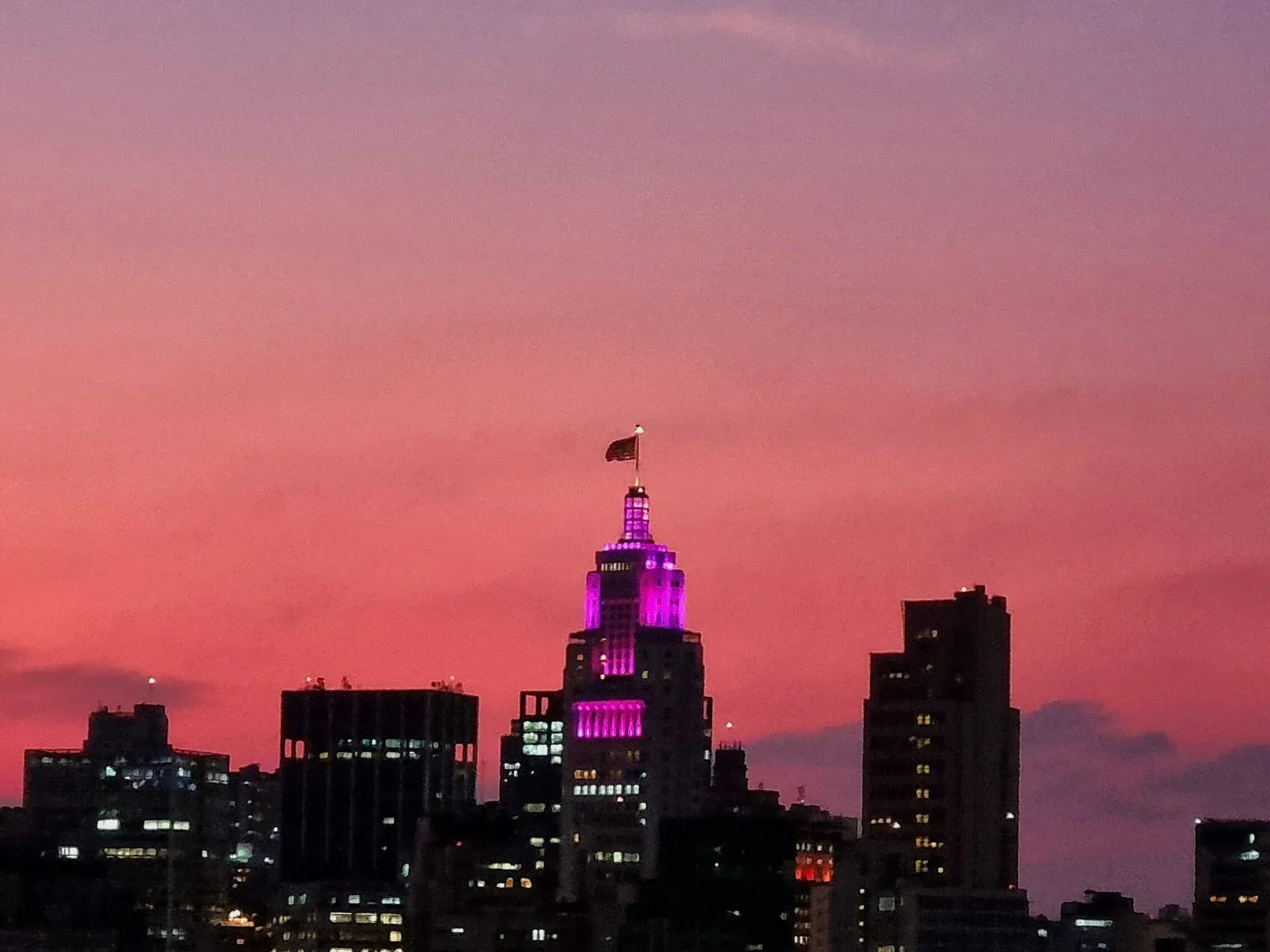 City skyline silhouetted against a pink and purple sunset sky.