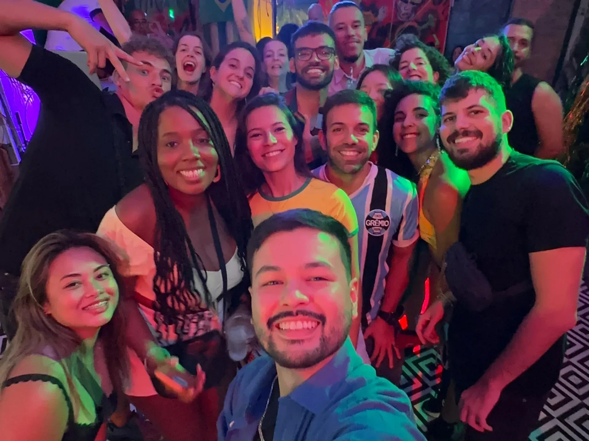Group of smiling friends posing closely together in a nightclub or bar