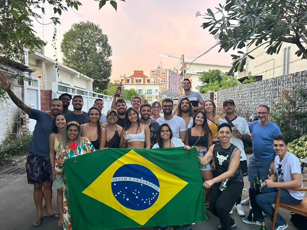 Group of people posing together outdoors while holding a Brazilian flag.