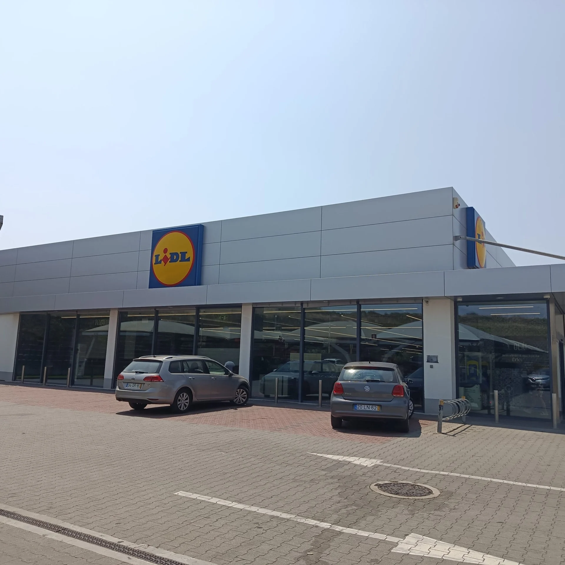 Lidl supermarket storefront with parked cars outside.