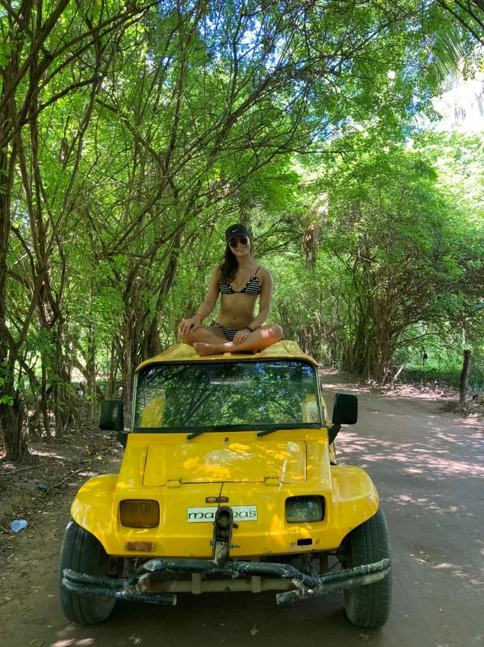 Woman sitting on a yellow off-road vehicle under trees on a forest trail