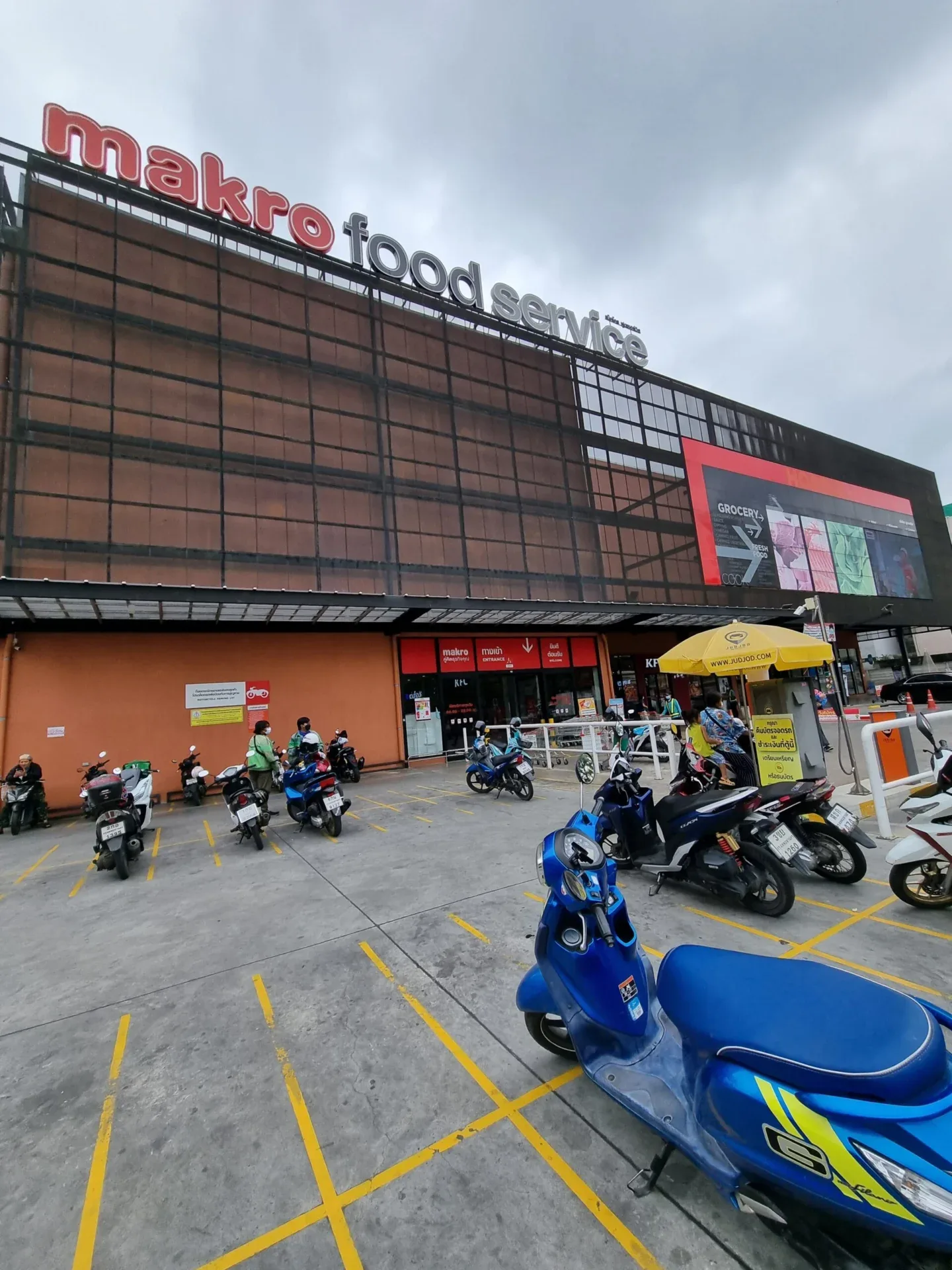 Makro supermarket exterior with parked scooters in front of the entrance.