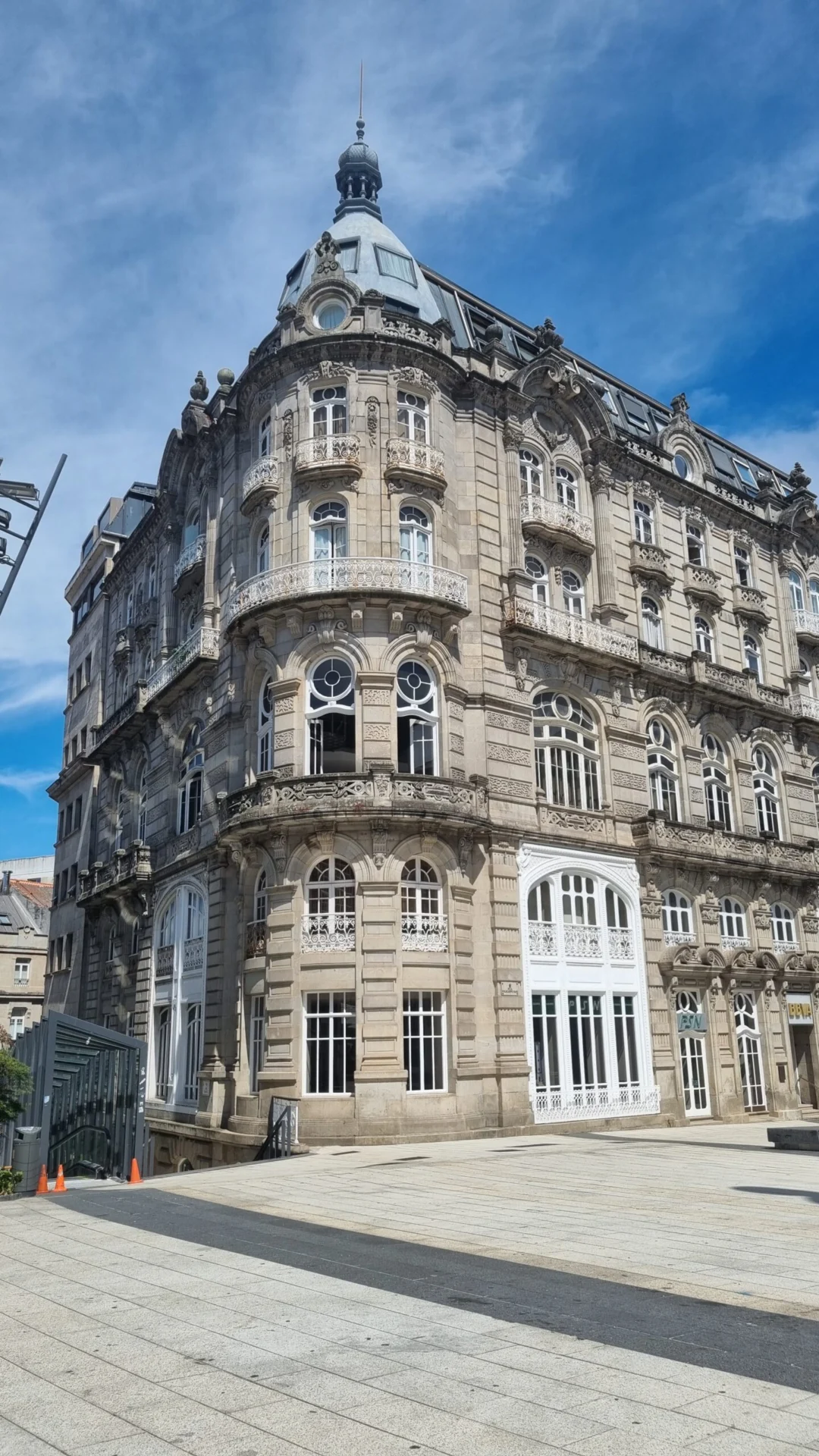 An ornate historic stone building rises beside an open plaza under a blue sky.