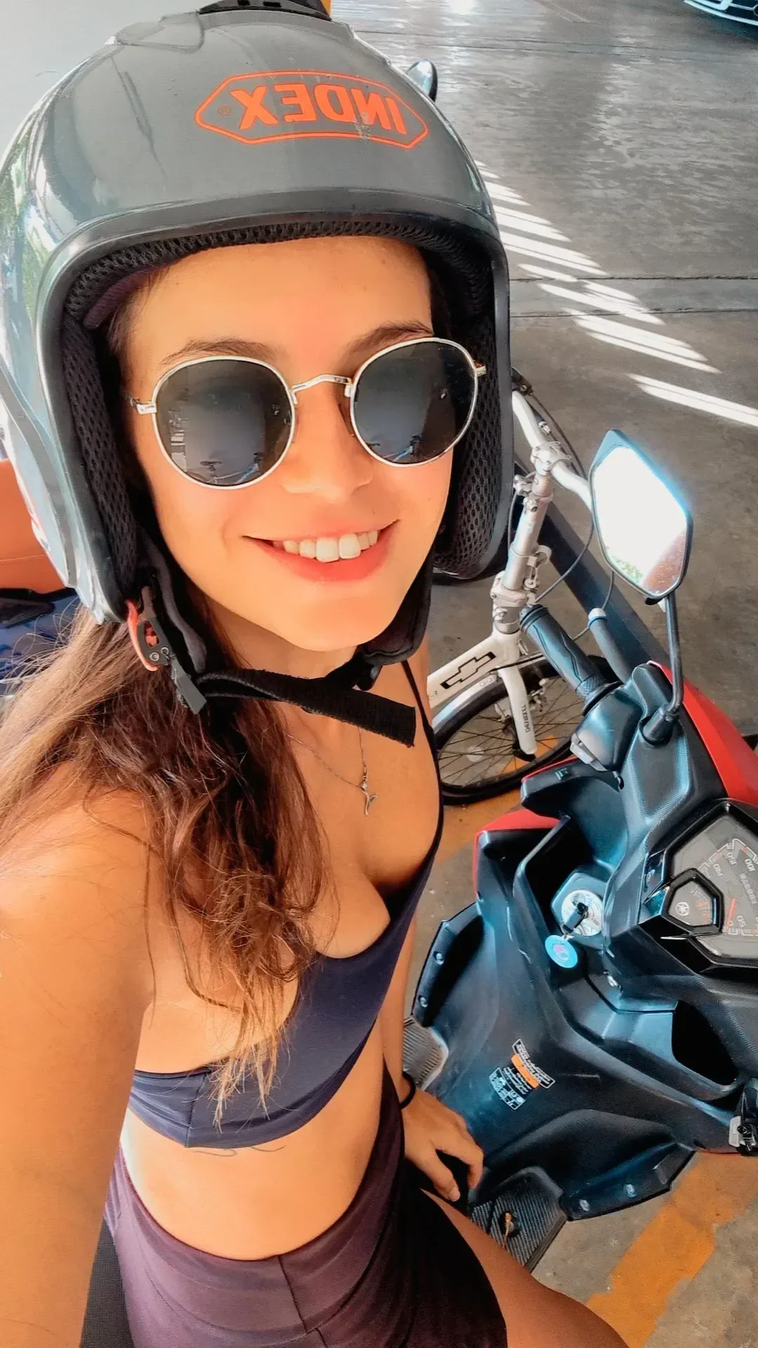 Woman in a helmet taking a selfie on a scooter.