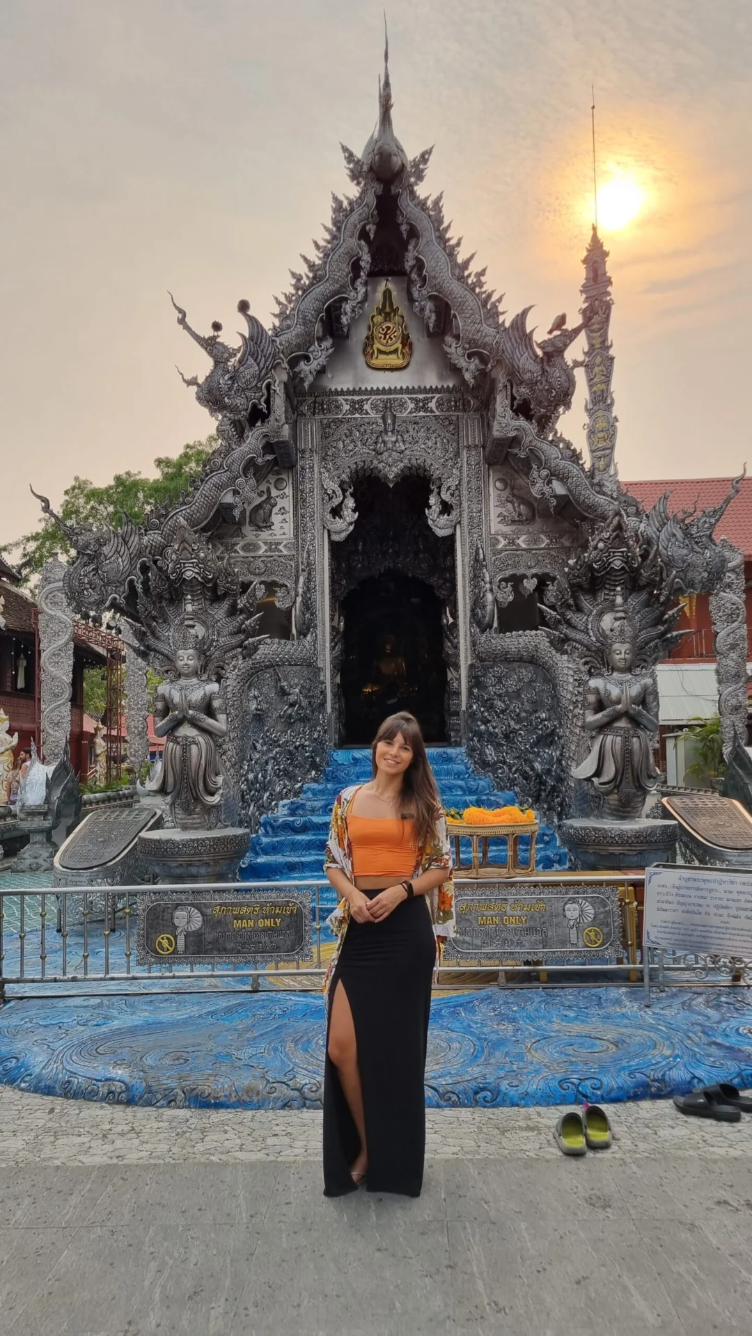 Silver temple entrance with a visitor standing in front at sunset.