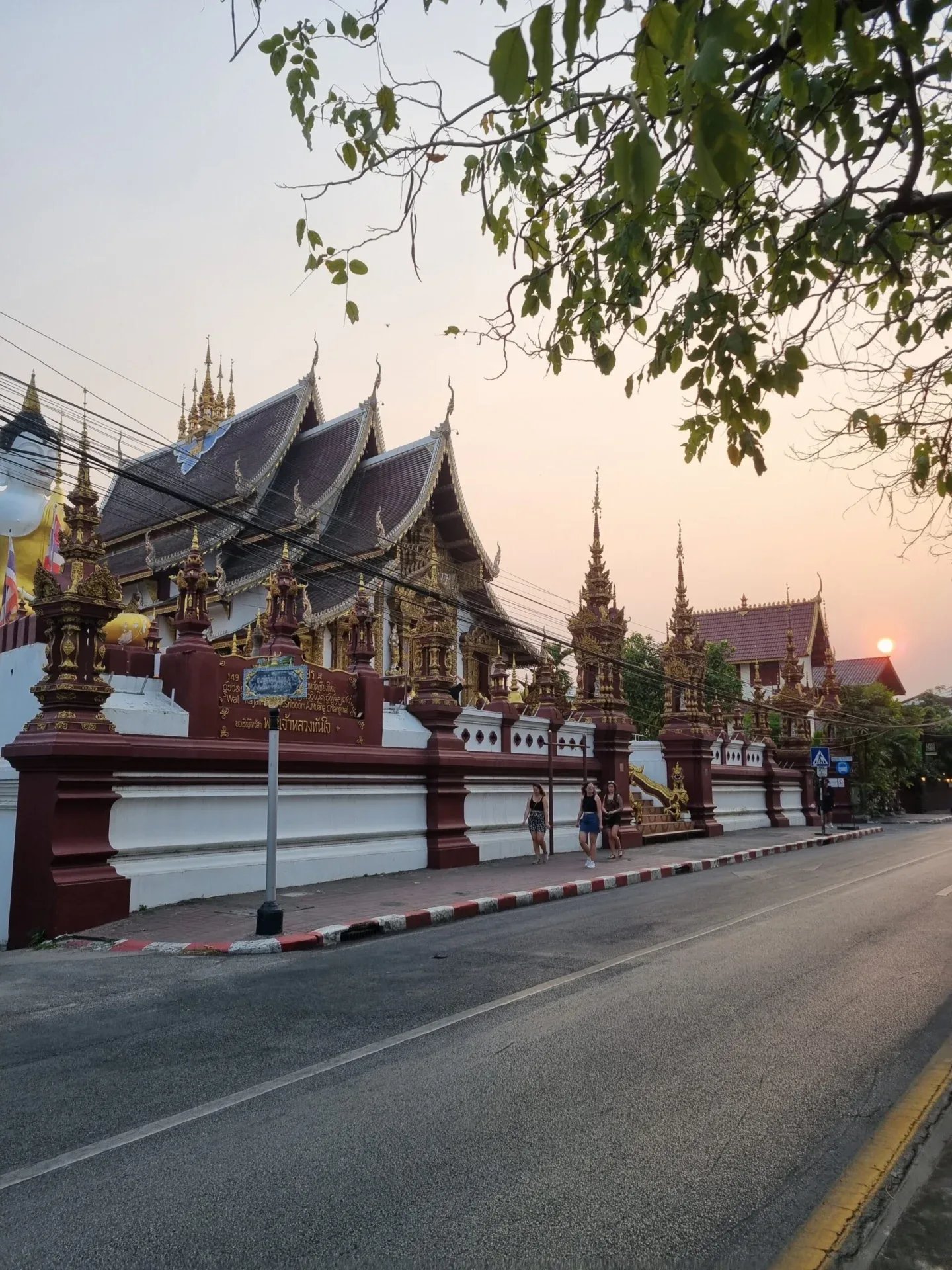 Thai temple complex along a quiet road at sunset.