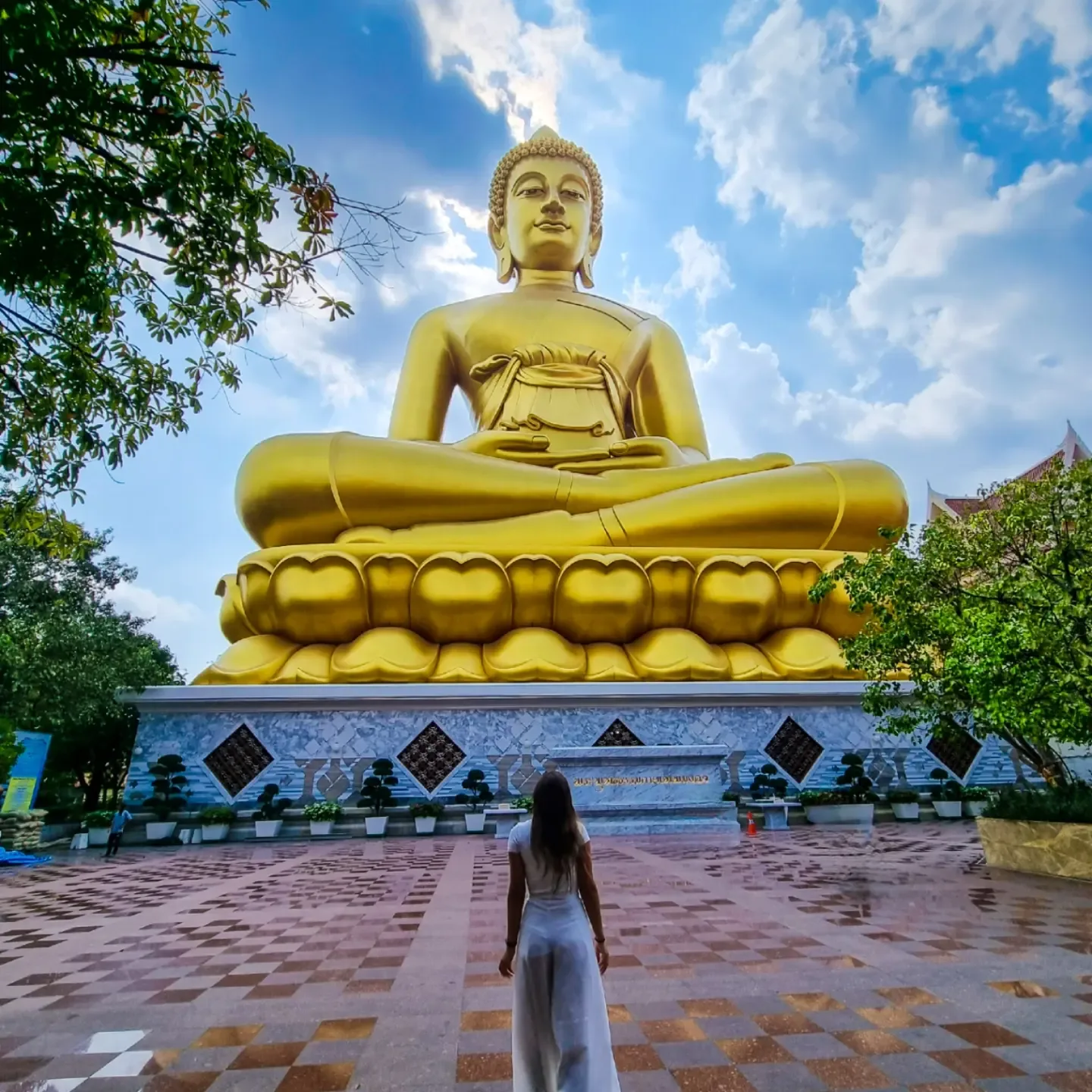 A giant golden Buddha statue rises above a temple courtyard in Bangkok.