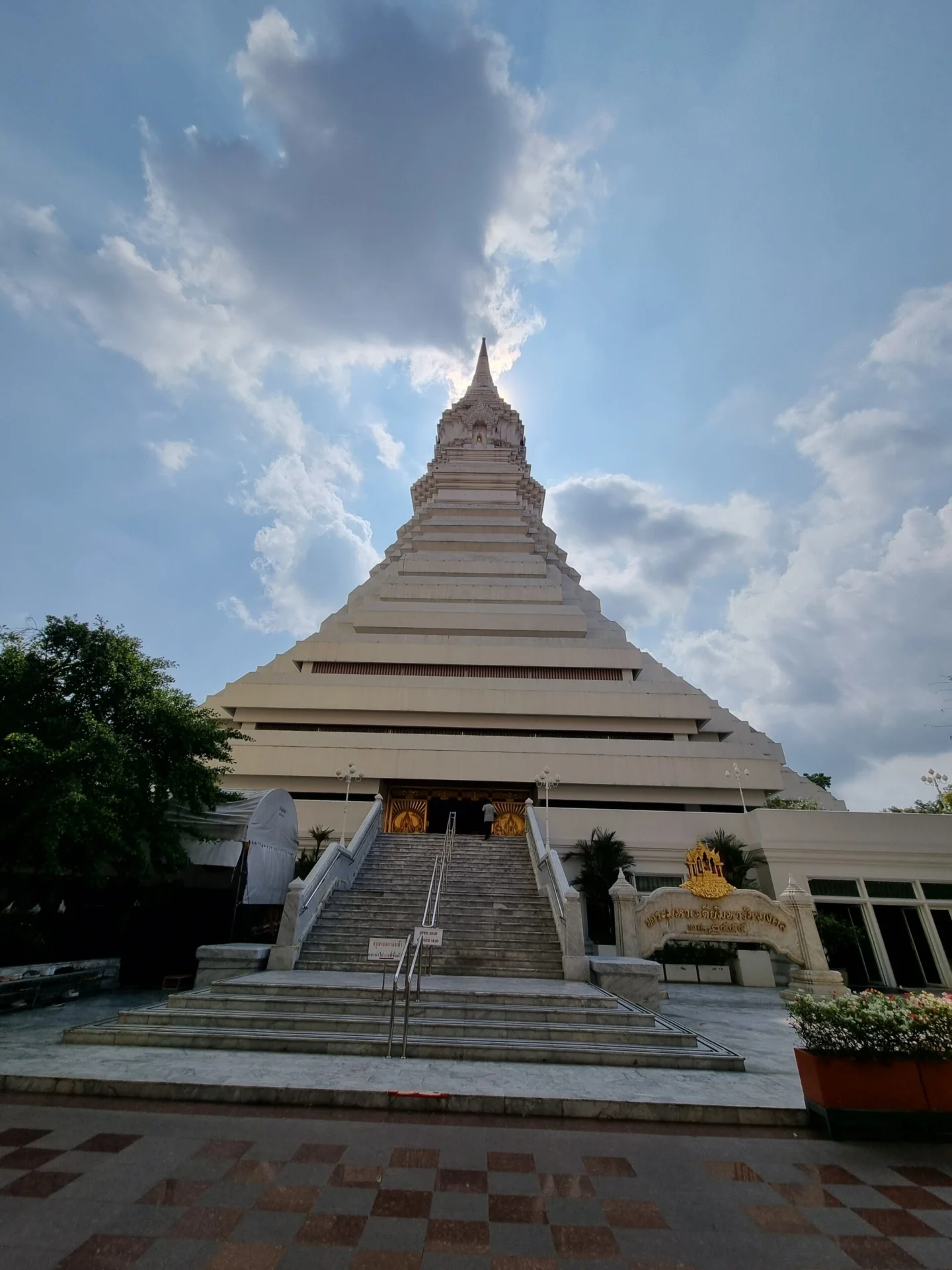White tiered stupa at Wat Paknam Phasi Charoen against a cloudy sky