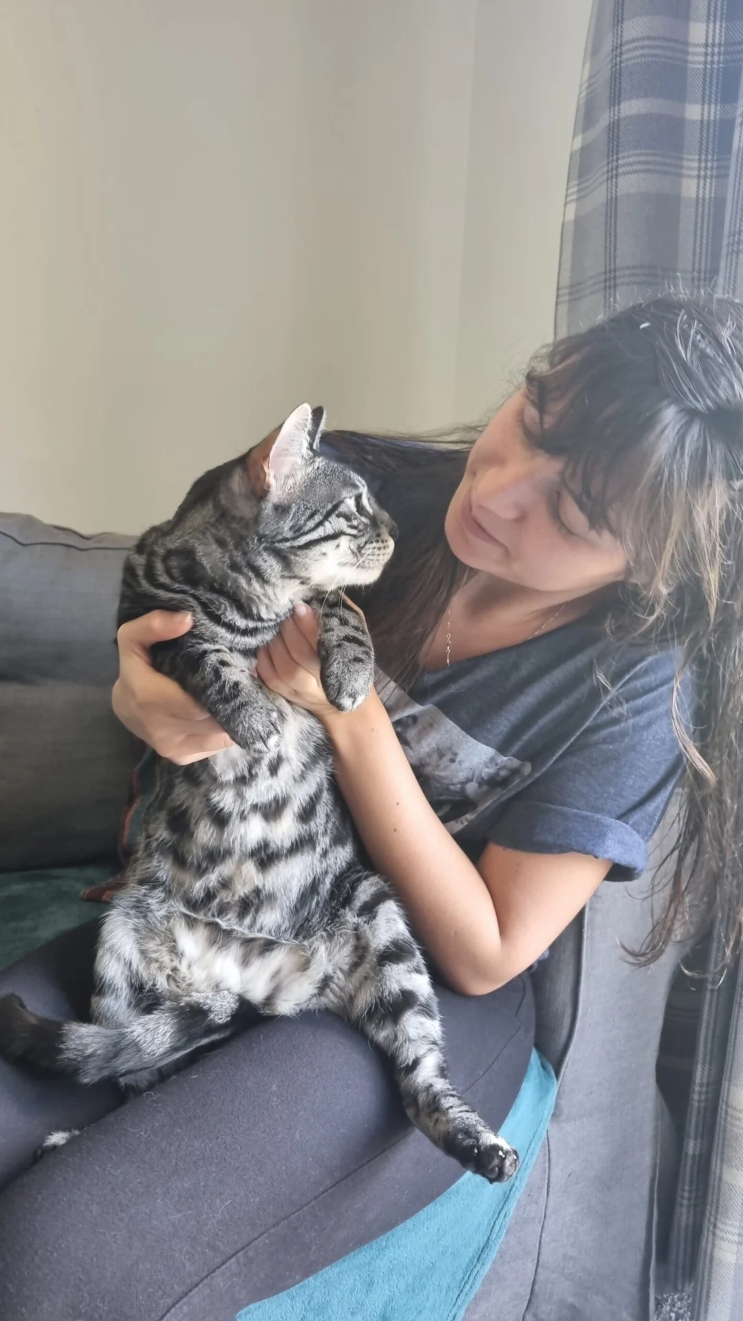 Woman sitting on a sofa holding a tabby cat in her arms